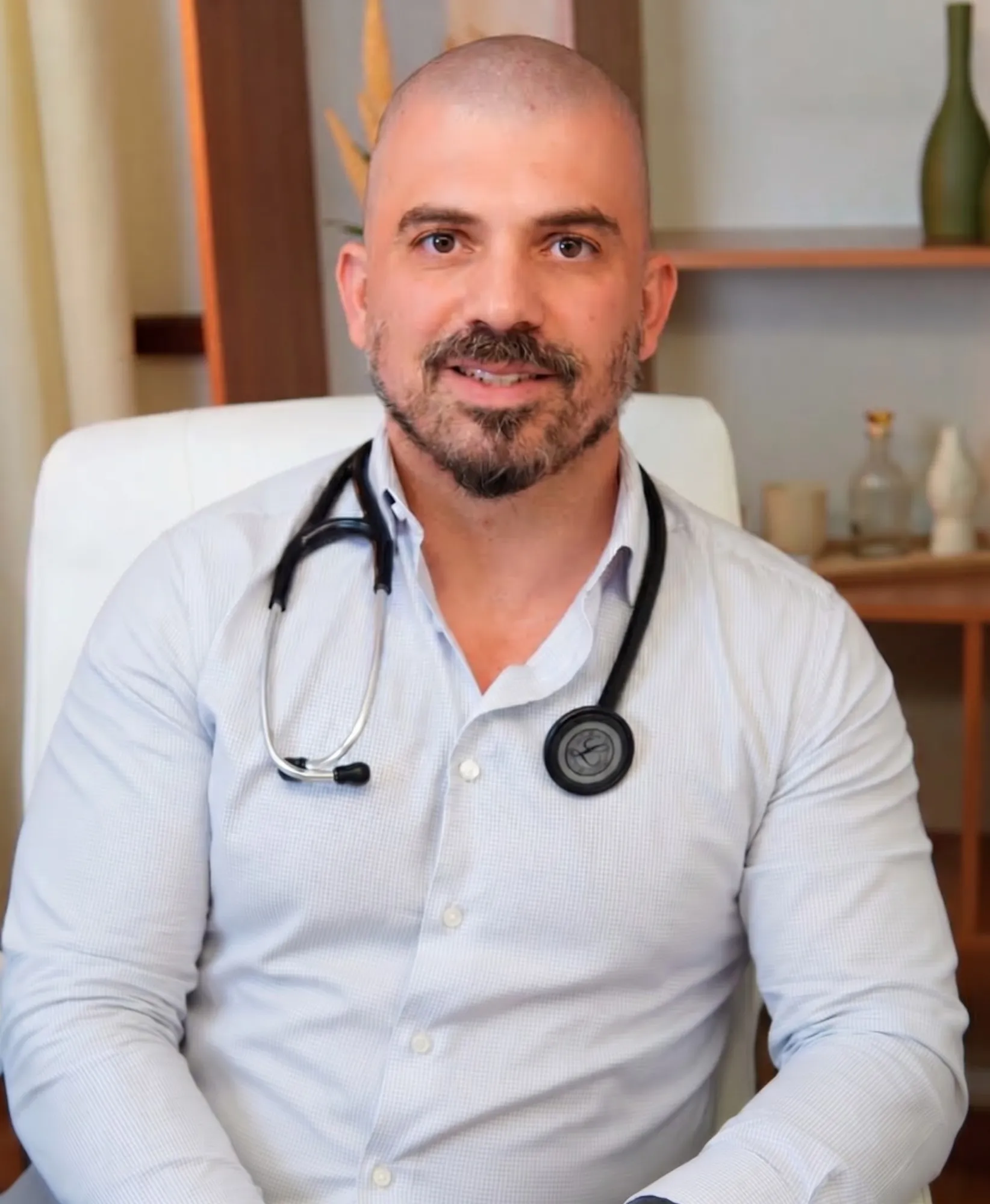 Dr. Cesar Buchalla Ferreira com estetoscópio, sentado em seu consultório